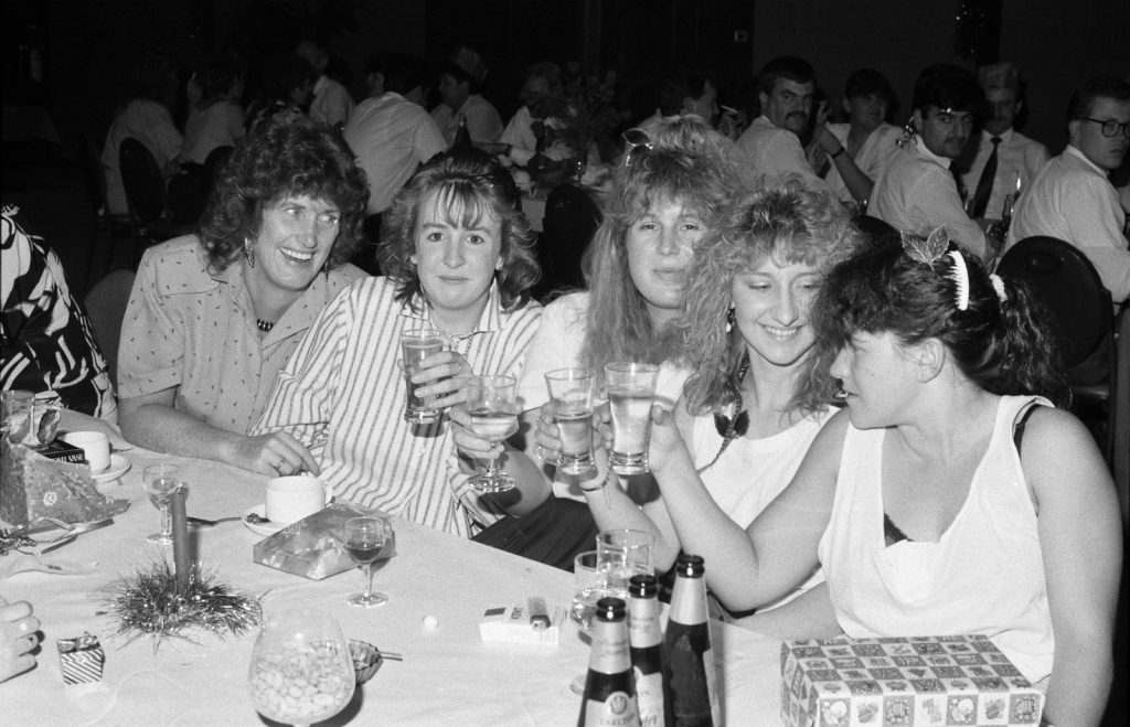 Black and white photo of women raising their glasses at a dining table