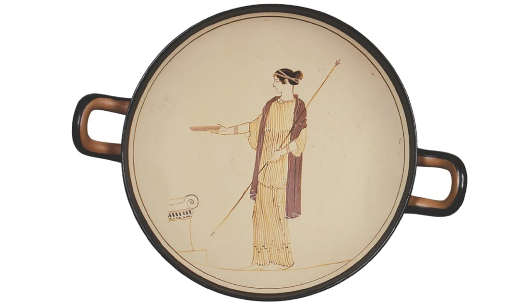 a woman wearing a gold-coloured Ionic chiton has a lavender chlamydon over her shoulder.