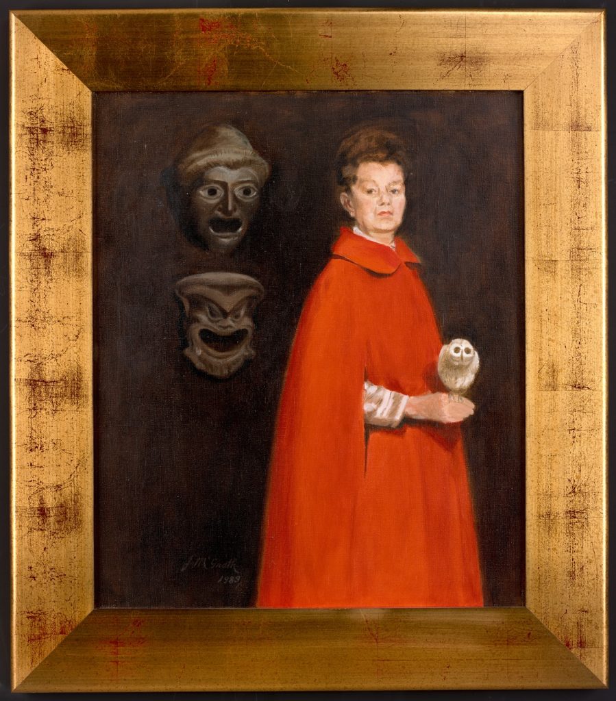 Potrait shows Peggy Glanville-Hicks wearing a red cloak with a snowy white owl perched on her hand to symbolise Athena, the goddess of wisdom. On the wall behind her hang two masks worn by actors in the ancient Greek theatre.