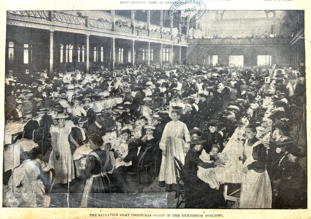 Black and white photo of hundreds of people sitting at long tables of food.