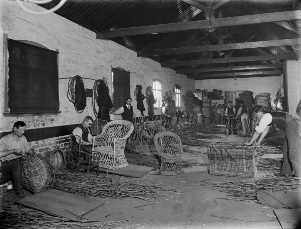 Men in a workshop making cane chairs and baskets.