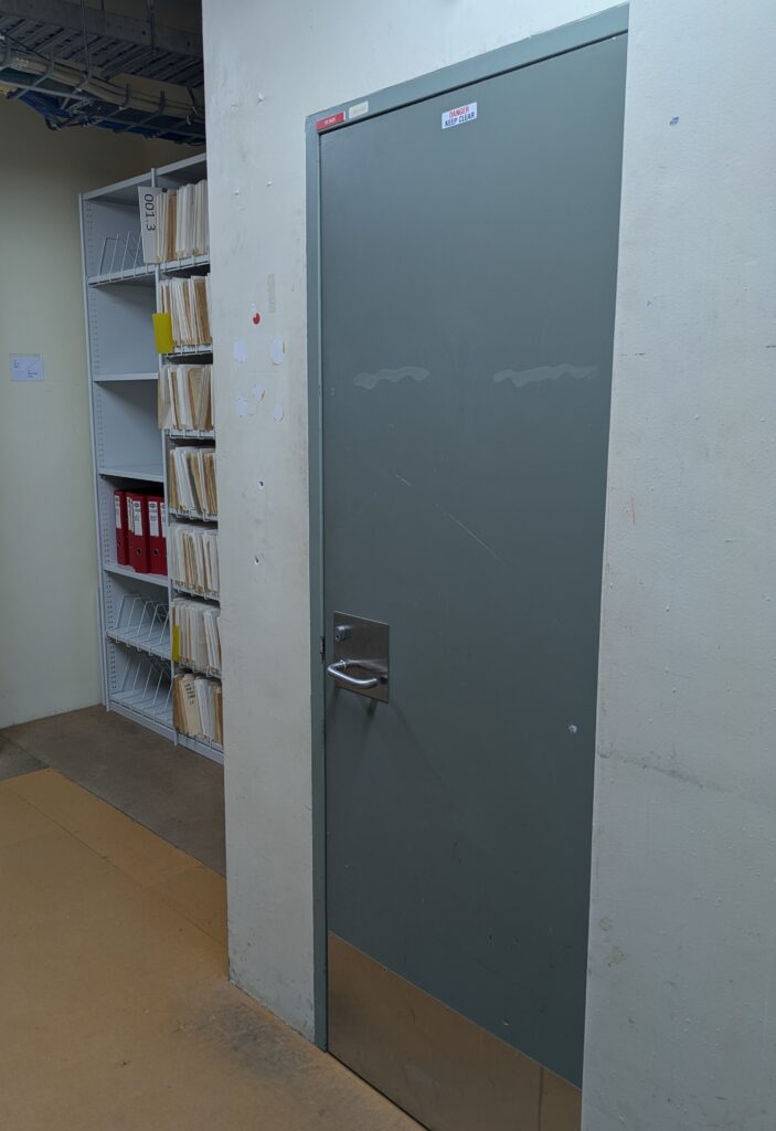 A photo of a cabinet of folders, tucked behind a doorway.