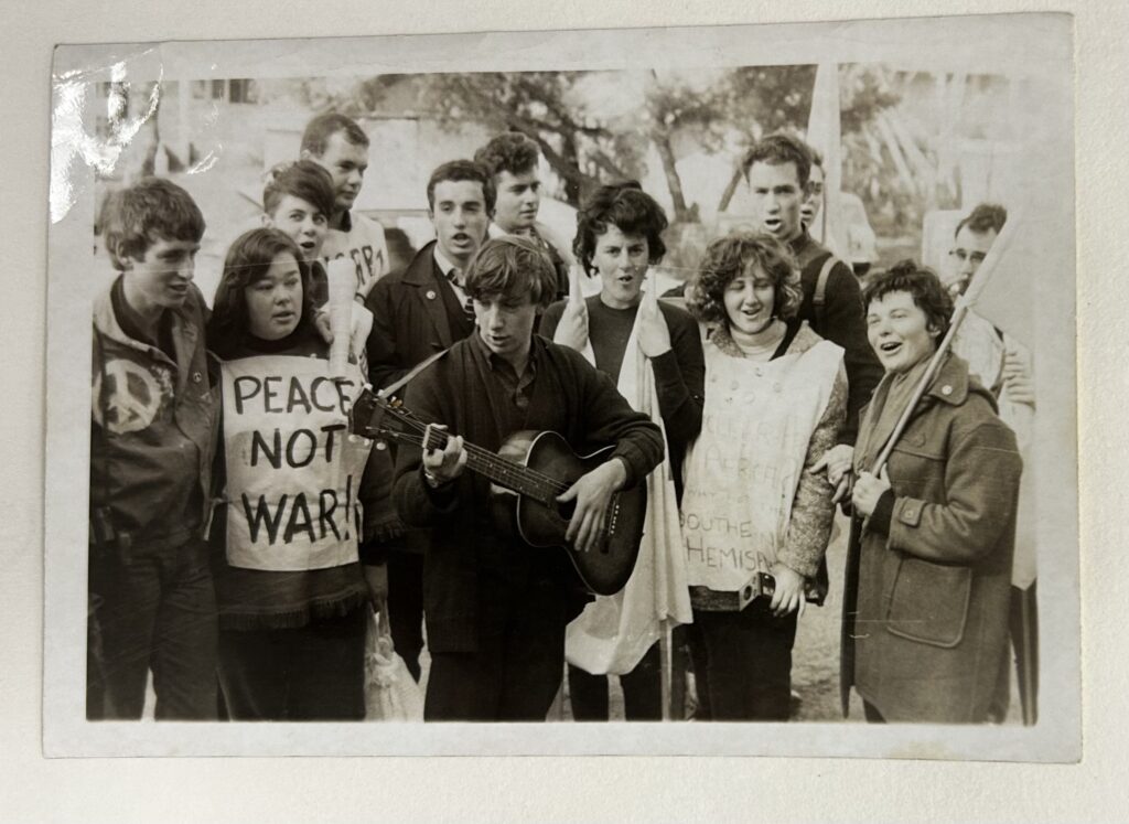 Photograph of 12 young people at a peace demonstration, carrying flags and signs.