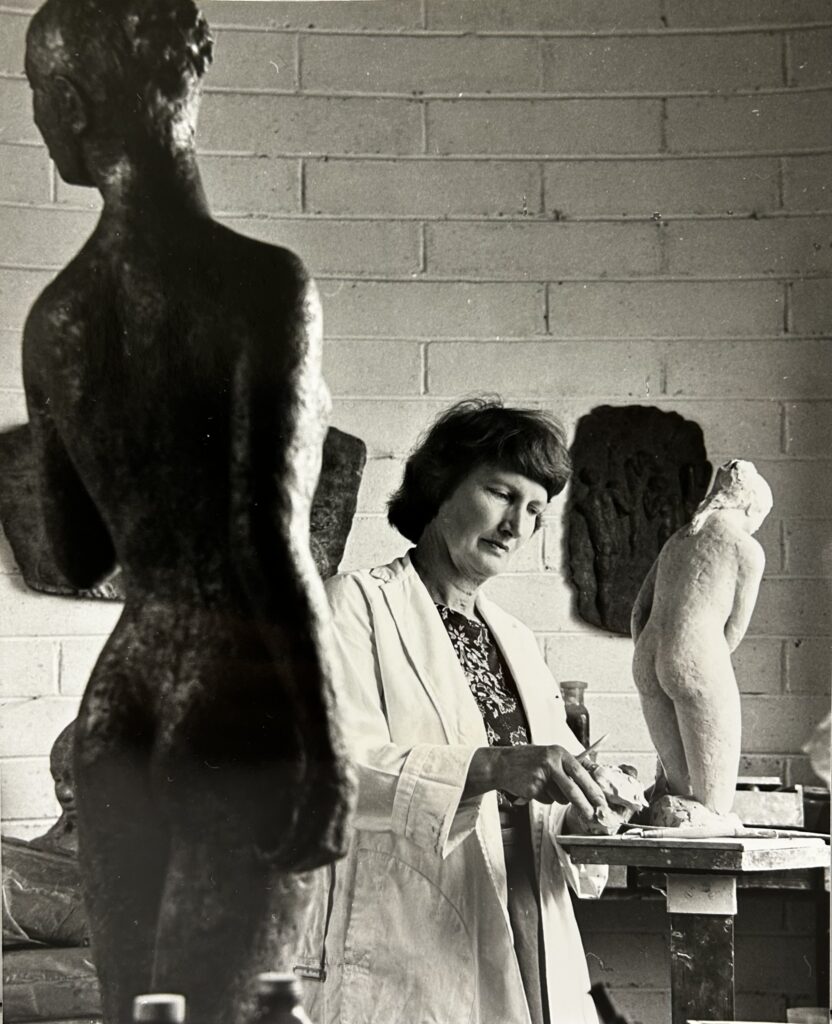 Photograph of Ailsa O'Connor in her studio, with plaster and bronze casts of her sculptures.
