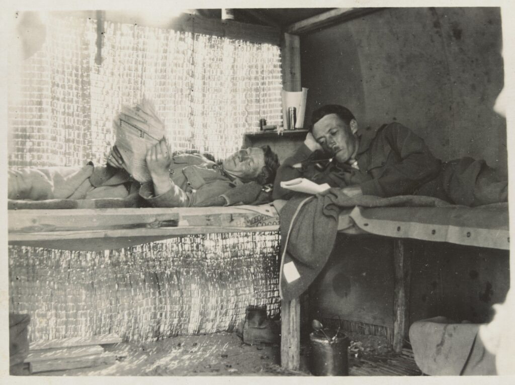 Two soldiers reading, whilst laying on their bunk beds.