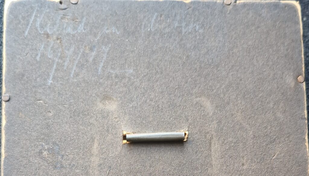 Image showing the top half of the back of a photo frame. Faint handwriting says Killed in action 16/7/17.
There is a small hook in the back of the frame.