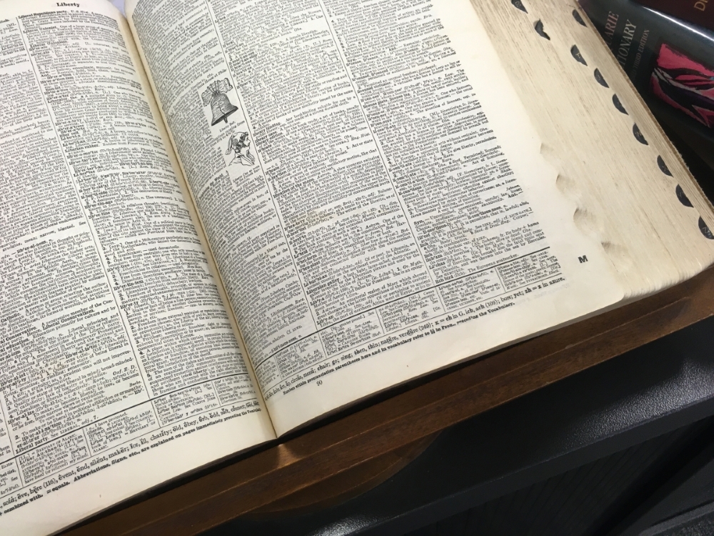 Colour photo of a Websters Dictionary open to the entry for 'Library'