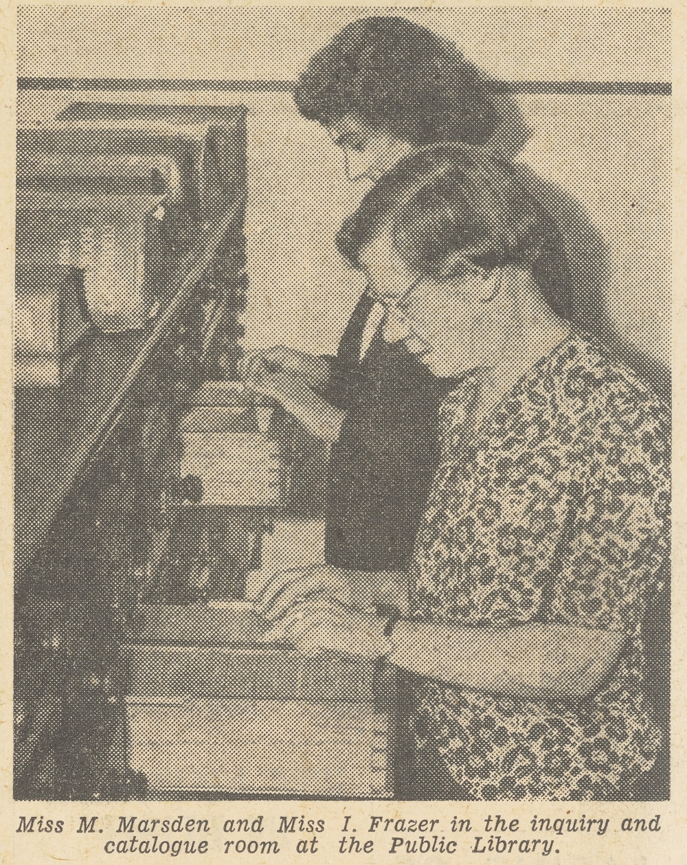 Black and white newspaper photograph of two librarians looking in card catalogues.