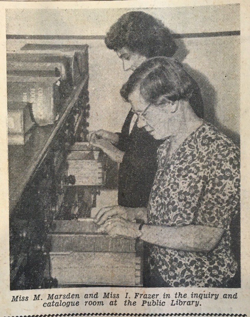 Black and white newspaper photograph of two librarians looking in card catalogues